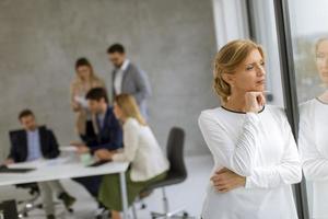 mulher olhando pela janela com uma reunião de negócios atrás dela foto