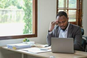 conceito esgotamento síndrome. africano americano homem de negocios sente desconfortável trabalhando, que é causou de estresse, acumulado a partir de mal sucedido trabalhos e Menos descansar corpo. consultar uma especialista psiquiatra. foto