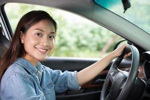 linda mulher asiática sorrindo e dirigindo um carro