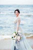 noiva com um buquê de flores na praia foto