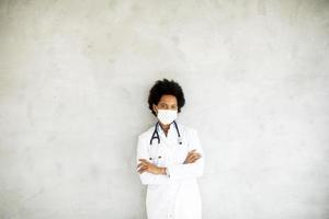 médico mascarado contra uma parede cinza com espaço de cópia foto