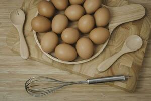 cozinha metal fio e cru ovos em a de madeira borda foto