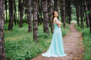 garota feliz em um vestido longo turquesa em um parque verde foto