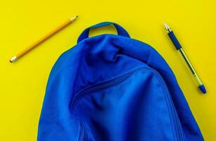 escola mochila, lápis, caneta em uma amarelo fundo. foto