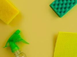 limpeza. plano deitar garrafa com limpeza produtos, esponjas e trapo em uma amarelo fundo. foto