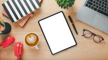 escritório escrivaninha local de trabalho com em branco tela tábua, computador portátil, óculos, caneta, caderno, fone de ouvido e copo do café, topo Visão plano deitar com cópia de espaço. foto