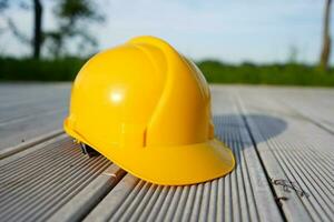 construção capacete em uma de madeira fundo. amarelo Difícil chapéu. foto