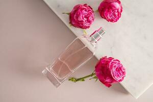 uma transparente garrafa do perfume ou Cosmético spray com três lindo rosas mentiras em uma branco mármore pódio. em branco garrafa layout. produtos anúncio. foto