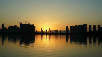 a lindo pôr do sol Visão com a edifícios' silhueta e laranja cor céu espelhado dentro a pacífico lago dentro a cidade foto