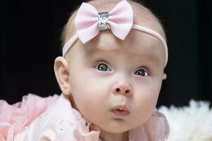 lindo bebê menina dentro Rosa roupas em uma Preto fundo. bebê às quatro meses velho. uma engraçado criança. foto