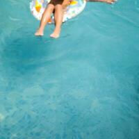 feliz indiano Garoto natação dentro uma piscina, criança vestindo natação traje ao longo com ar tubo durante quente verão Férias, crianças Garoto dentro grande natação piscina. foto