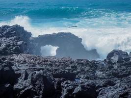 ondas atlânticas encontrando um arco de rocha em el golfo, na costa vulcânica das ilhas canárias de lanzarote foto
