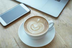 Cuide de sua xícara de café de conceitos de saúde na mesa de madeira com smartphone e laptop no escritório