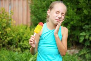 menina tem dor de dente a partir de frio gelo creme. foto