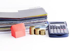 papel da casa vermelha e pilha de moedas e calculadora e guia de pagamento de contas para conceito de empréstimos foto