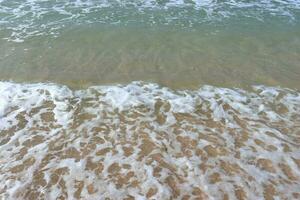 água espuma com suave areia. oceano costa com arenoso de praia e avançando aceno. foto