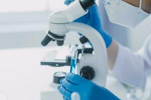 mão do cientista com teste tubo e frasco dentro médico química laboratório azul bandeira fundo foto