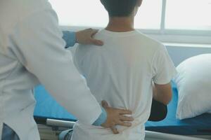 médico ou fisica terapeuta examina costas dor e espinhal área para dar adendo dentro a reabilitação Centro. foto