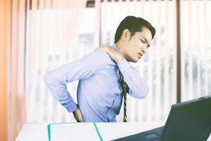 homem asiático com dor nas costas no escritório foto