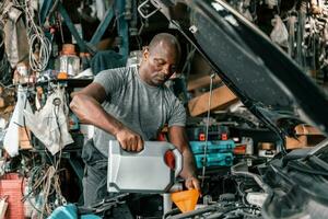 auto mecânico diagnosticar e solução de problemas com Ferramentas e equipamento. polimento carro, fixação travagem e direção sistemas. medindo óleo níveis com óleo calibre bastão e então derramando ou mudando isto. foto