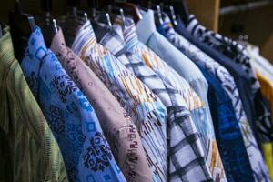 colorida variedade do camisas enforcamentos dentro uma roupas showroom. aglomerado foco foto