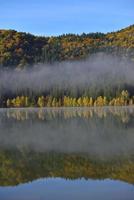 paisagem de outono nas montanhas com árvores refletindo na água no lago st ana romênia foto