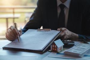 agente imobiliário dá caneta e documento acordo com o cliente para assinar contrato. acordo de conceito foto