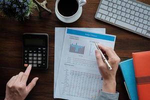 conceito de contabilidade de negócios, homem de negócios usando caneta apontando com gráfico de planejador de orçamento de dados e calculadora para calcular papel de plano de finanças no escritório. foto