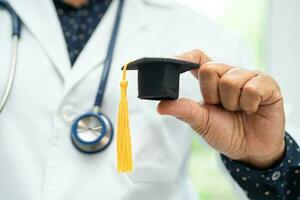 estudo de médico asiático aprende com chapéu de graduação na enfermaria do hospital, conceito de medicina de educação de gênio brilhante inteligente. foto