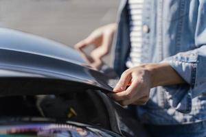 mulher olhando para o carro para resolver um problema foto