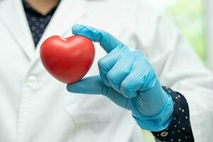 médico segurando um coração vermelho na enfermaria do hospital, conceito médico forte e saudável. foto