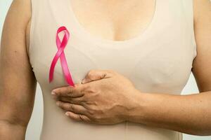 paciente mulher asiática verificando e preocupando seu peito, auto-exame de mama ou bes, símbolo do dia mundial do câncer de mama. foto