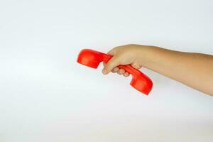 vermelho brinquedo telefone dentro a criança mão. fechar-se do uma criança mão. isolado em uma branco fundo. a conceito do a publicidade bandeira. foto