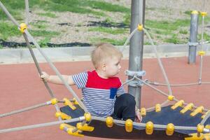 uma pequeno Garoto entusiasticamente tocam em a Parque infantil. sucesso, criativo Ideias e Esportes conceitos. crianças Parque infantil. foto