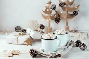 dois canecas com cacau e marshmallows dentro Natal decorações em uma branco de madeira mesa. ecológico feriado foto