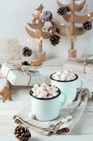 dois canecas com cacau e marshmallows dentro Natal decorações em uma branco de madeira mesa. ecológico feriado. vertical Visão foto