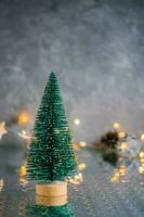 Natal decorativo fofo abeto árvore em uma cinzento fundo com embaçado luzes. Natal fundo. cópia de espaço. vertical Visão foto