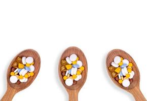 comprimidos de medicamento em colheres de madeira em fundo branco com espaço de cópia foto