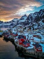 vermelho pescaria cabines dentro lofoten Noruega dentro pôr do sol de drone, neve montanhas foto