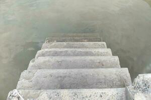 cimento escadas estendido para dentro a água. foto