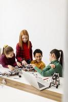crianças felizes programando brinquedos elétricos e robôs na sala de aula de robótica