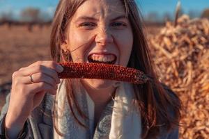 garota segura um pedaço de milho perto da boca