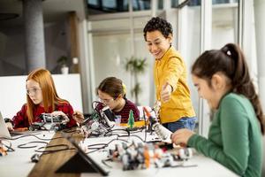 crianças felizes programando brinquedos elétricos e robôs na sala de aula de robótica