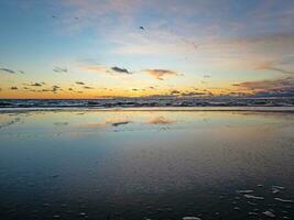pôr do sol sobre o mar com reflexos nas ondas crescentes foto