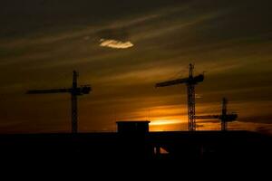 pitoresco pôr do sol com nuvens dentro a céu dentro a cidade com construção guindastes, foto