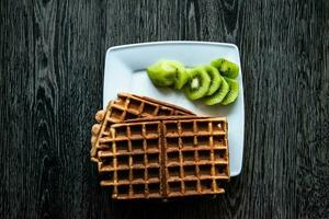 sem aditivos banana waffles servido com verde kiwi em uma branco quadrado prato foto