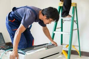 técnico homem instalando a ar condicionamento dentro uma cliente casa, reparador fixação ar condicionador unidade, manutenção e reparação conceitos foto