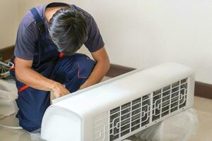 técnico homem instalando a ar condicionamento dentro uma cliente casa, jovem reparador fixação ar condicionador unidade, manutenção e reparação conceitos foto