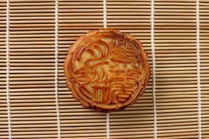 chinês cozido decorado mooncake meio outono festival quadrado lua bolo o preenchimento presente desejo oferta em bambu esteira sobre de madeira mesa foto