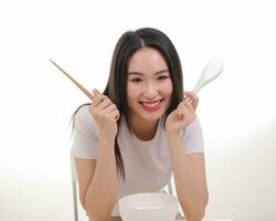 lindo jovem sul leste ásia mulher segurando chinês esvaziar pauzinho sopa colher tigela utensílio fingir agindo posando Vejo comer gosto alimentação oferta satisfação gostoso branco fundo feliz foto